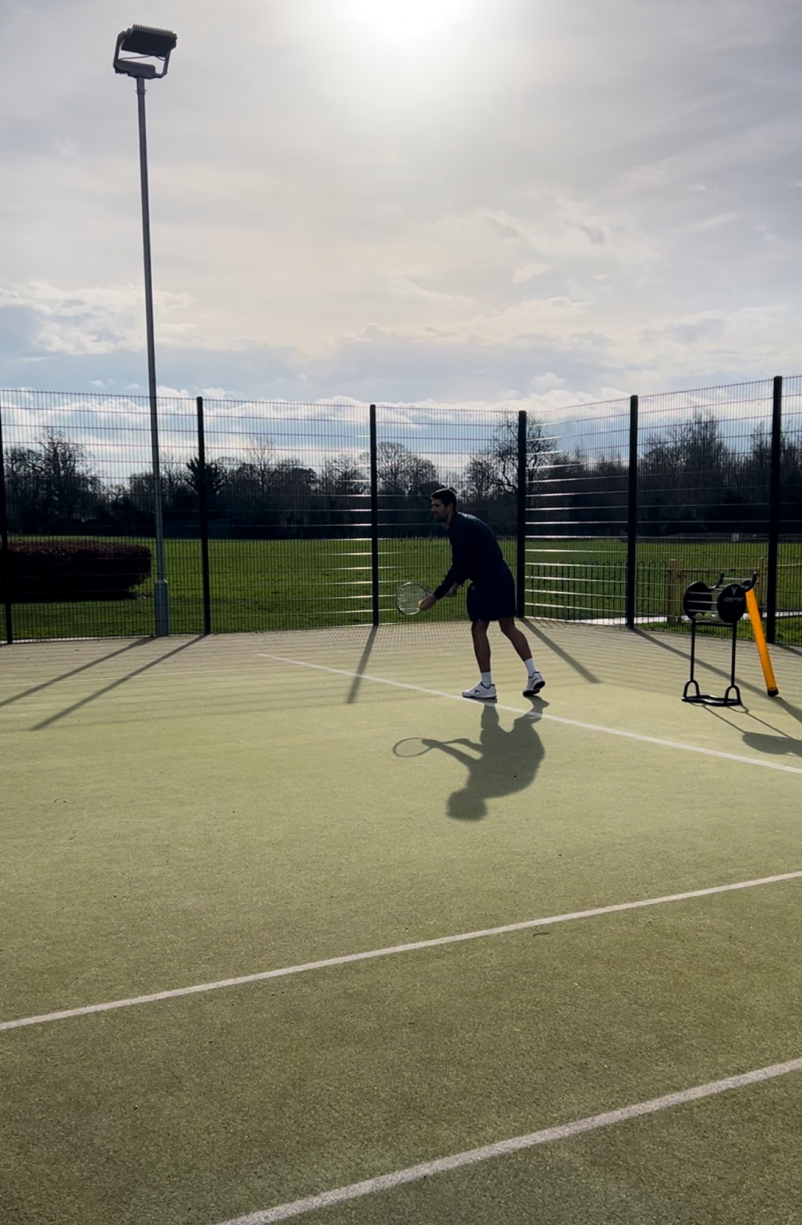 Mark Hunter playing a volley on an outdoor tennis court at golden hour